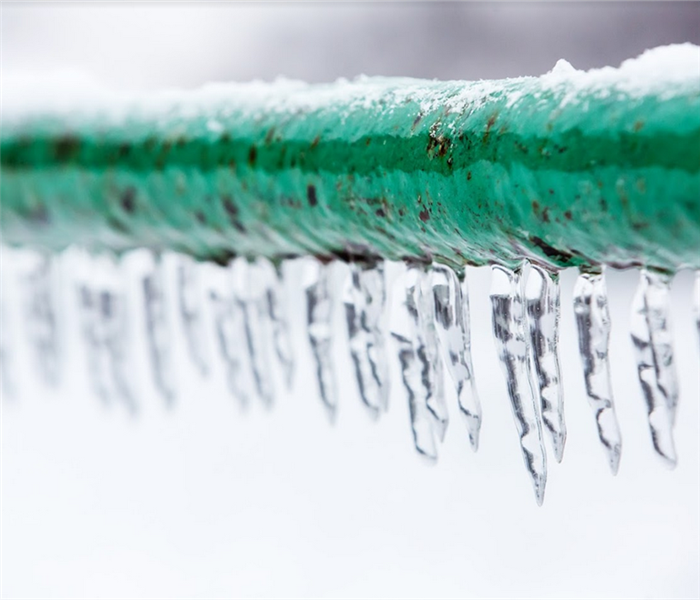 icicles hanging off of a frozen green pipe