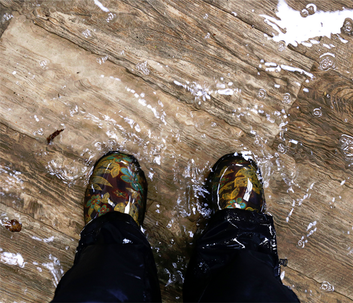 a persons boots standing in a flooded room with water covering the floor