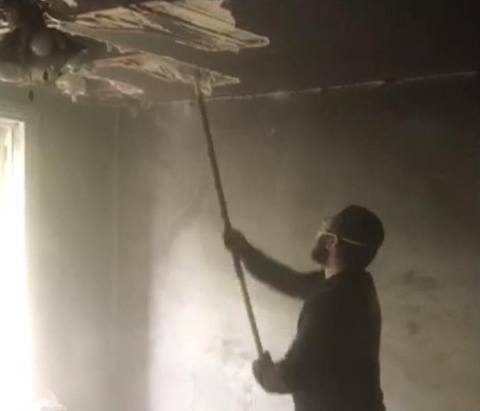 SERVPRO technician removing a fire damaged ceiling